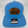 Richardson 112 patch hat in Columbia blue with white mesh, featuring a laser-engraved leather patch reading "Hoochie Daddy" on the front panel.