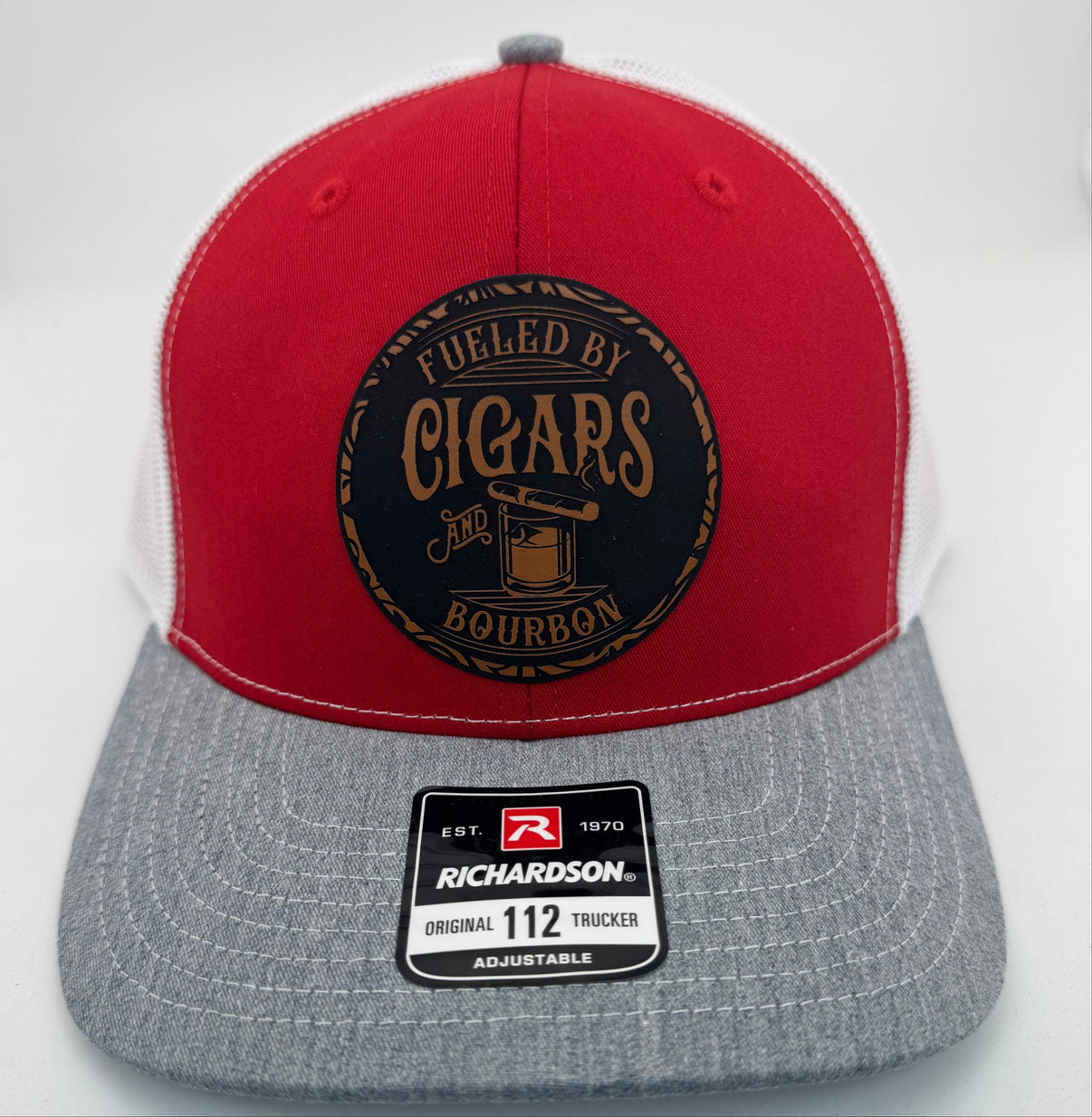 Richardson 112 trucker hat with custom laser engraved leather patch featuring Fueled by Cigars and Bourbon logo, Red, White, and Heather Grey scheme