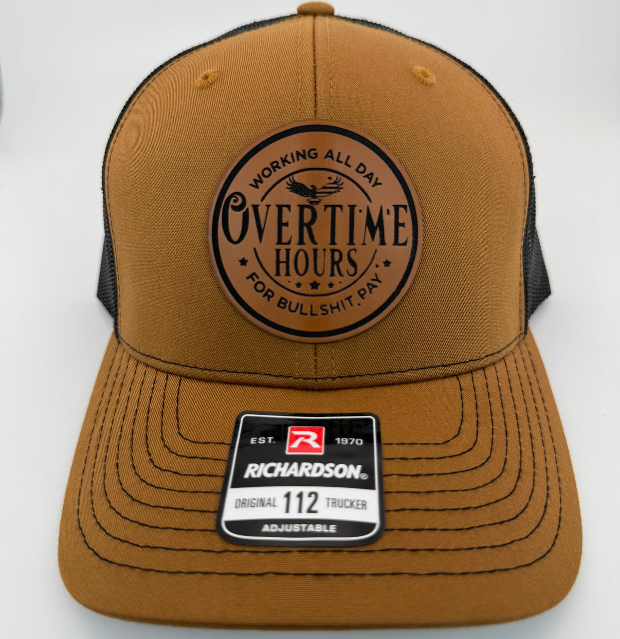 Richardson 112 trucker hat with custom laser engraved leather patch featuring Overtime Hours, Working All Day For Bullshit Pay logo, Carmel and Black color scheme