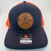 Richardson 112 trucker hat with custom laser engraved leather patch featuring Overtime Hours, Working All Day For Bullshit Pay logo, Navy and Orange Mesh color scheme