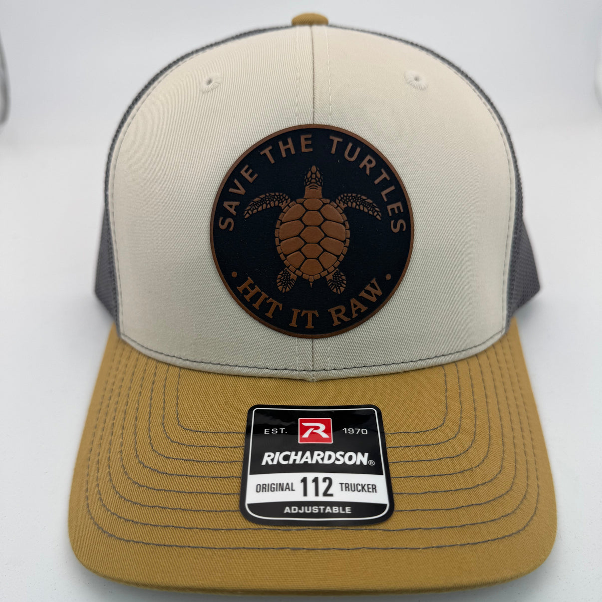 Richardson 112 trucker hat with custom laser engraved leather patch featuring Save the Turtles, Hit it Raw logo, Mink Beige, Charcoal, and Amber Gold 
color scheme