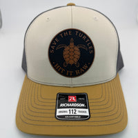 Richardson 112 trucker hat with custom laser engraved leather patch featuring Save the Turtles, Hit it Raw logo, Mink Beige, Charcoal, and Amber Gold 
color scheme